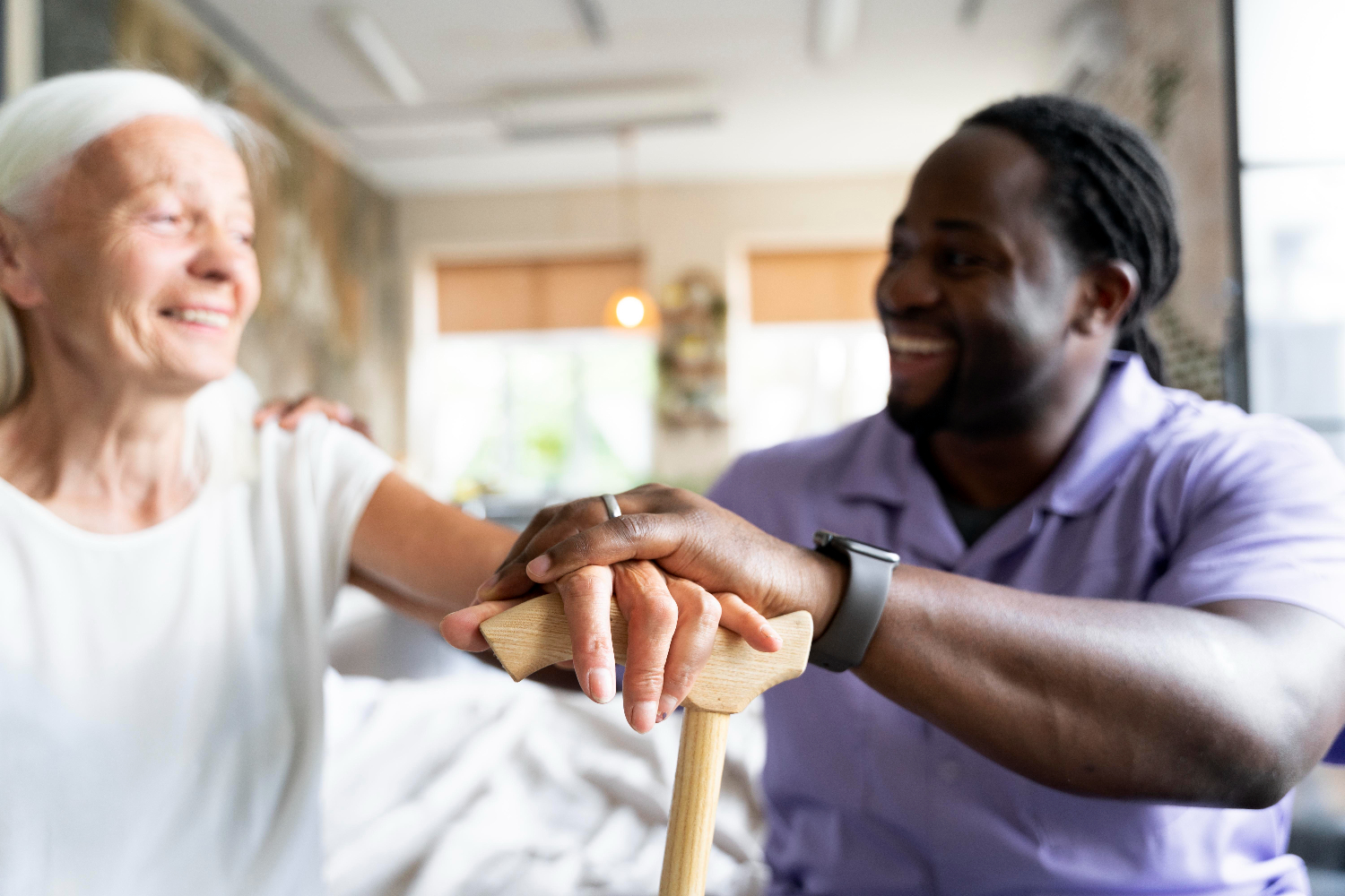 Caregiver helping elderly woman with walking cane